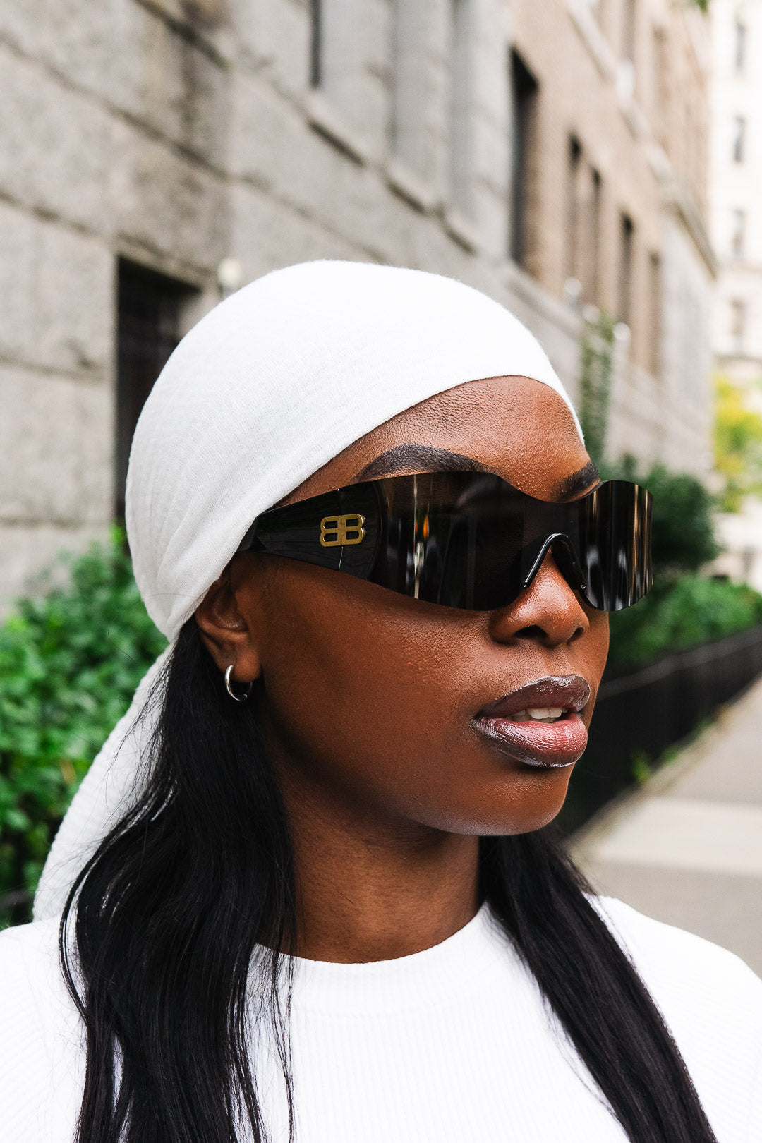 Woman wearing a white headscarf and sunglasses in an urban setting